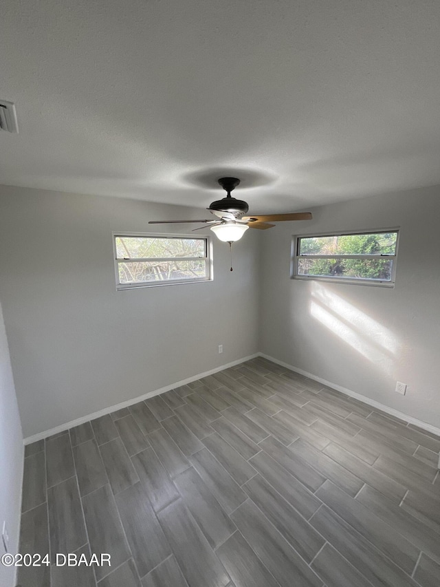 empty room featuring hardwood / wood-style flooring, ceiling fan, and a textured ceiling