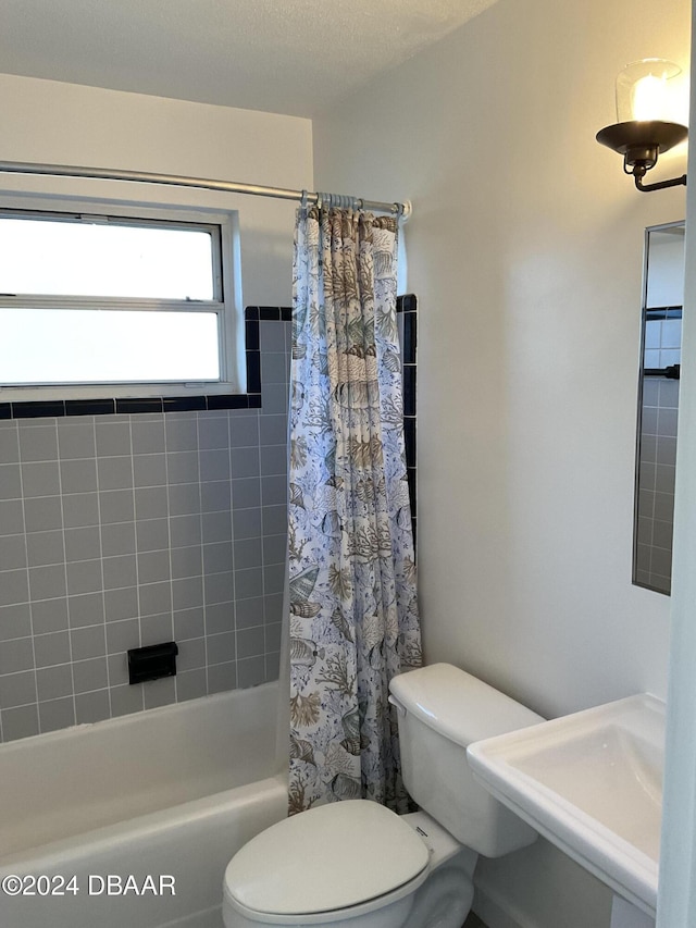 full bathroom featuring toilet, shower / tub combo with curtain, a textured ceiling, and sink