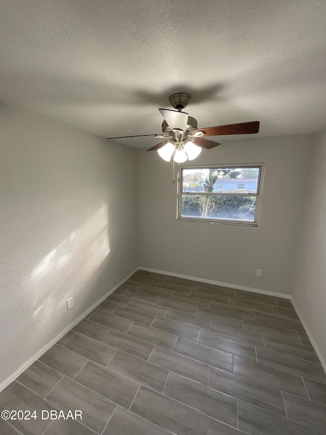 spare room featuring a textured ceiling, ceiling fan, and dark wood-type flooring