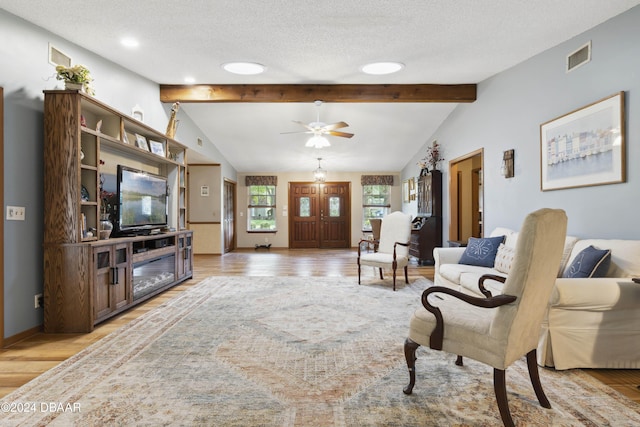 living room with ceiling fan, vaulted ceiling with beams, a textured ceiling, and light hardwood / wood-style flooring