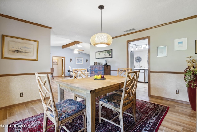 dining space with ceiling fan, lofted ceiling with beams, crown molding, and light hardwood / wood-style floors