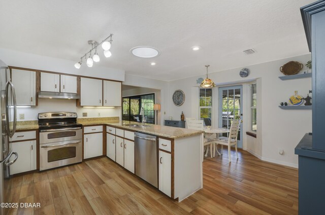 interior space featuring ceiling fan with notable chandelier, light wood-type flooring, and vaulted ceiling with beams