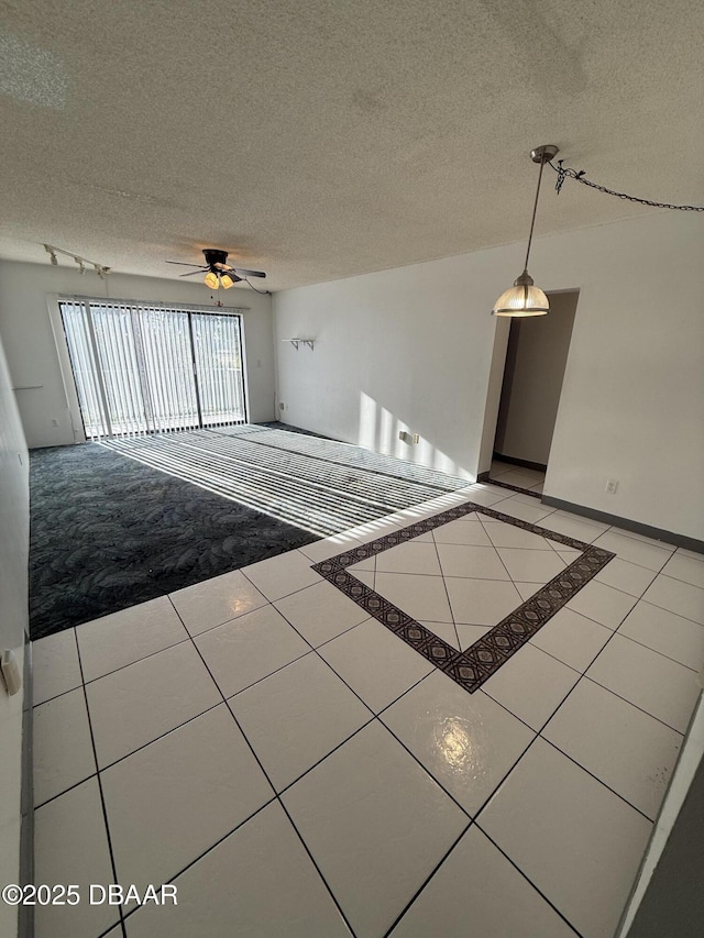 tiled spare room with ceiling fan and a textured ceiling