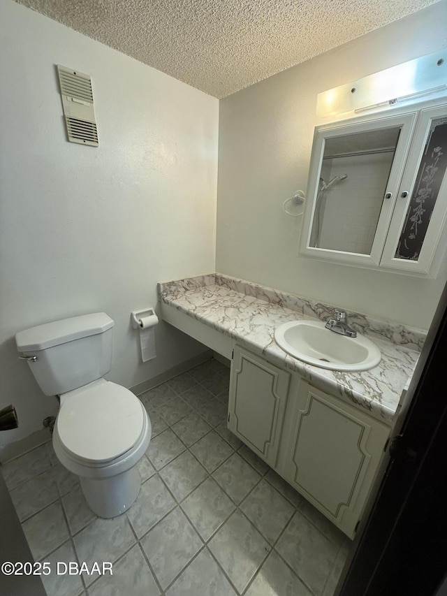 bathroom with vanity, toilet, tile patterned flooring, and a textured ceiling