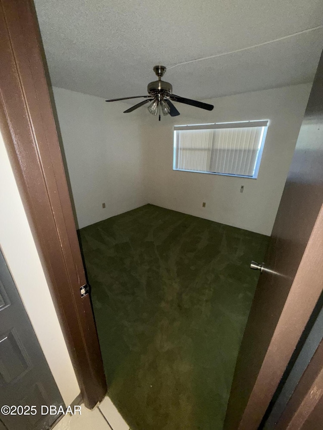 carpeted empty room with ceiling fan and a textured ceiling