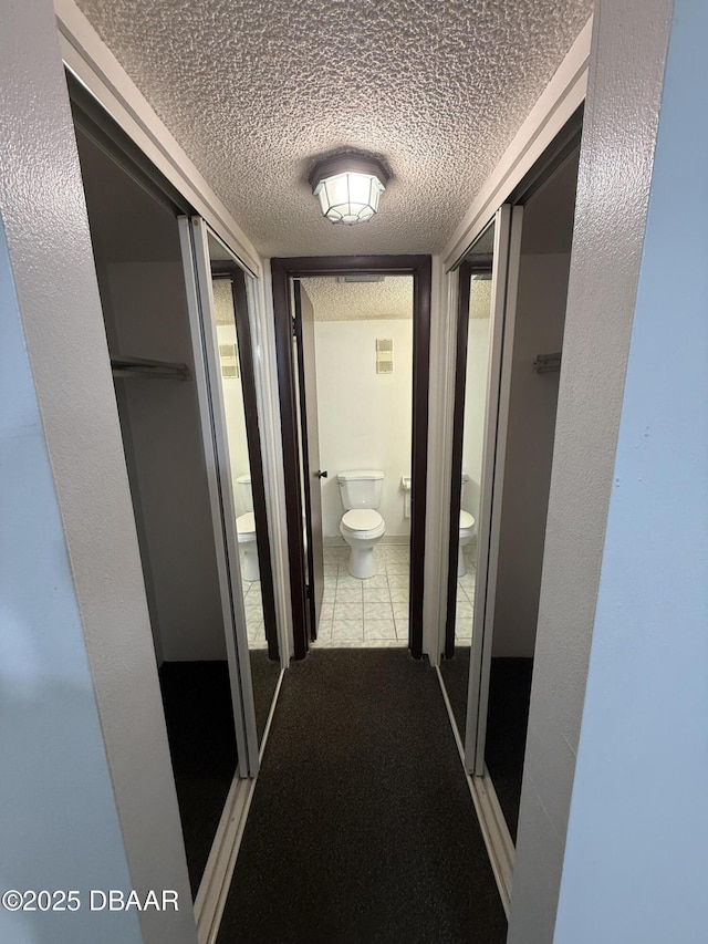 hall featuring light carpet and a textured ceiling