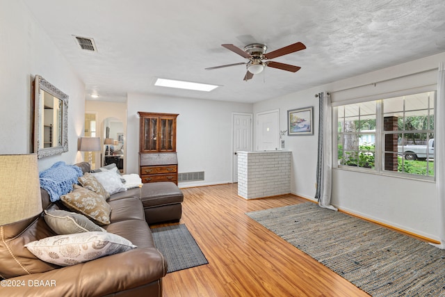 living room featuring hardwood / wood-style flooring, ceiling fan, and a textured ceiling