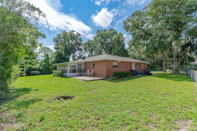 rear view of property featuring a patio, a sunroom, and a lawn