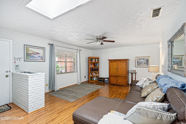 living room with ceiling fan, a textured ceiling, and light hardwood / wood-style flooring