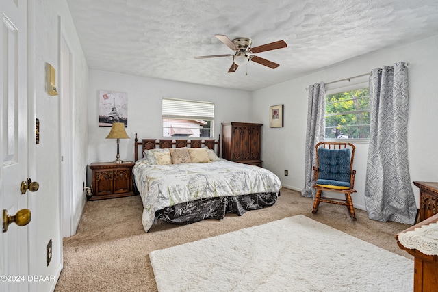 carpeted bedroom featuring ceiling fan, multiple windows, and a textured ceiling