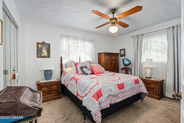 carpeted bedroom with a textured ceiling, ceiling fan, and a closet