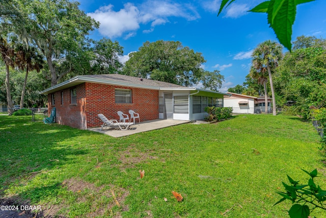 back of house featuring a lawn, a sunroom, and a patio area