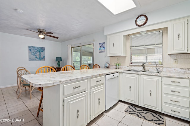 kitchen featuring white cabinetry, sink, kitchen peninsula, white dishwasher, and a kitchen bar