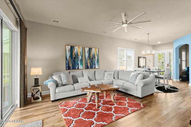 6341 Hanfield Dr, Port Orange, FL 32128 - living area with visible vents, baseboards, arched walkways, light wood-style floors, and ceiling fan with notable chandelier