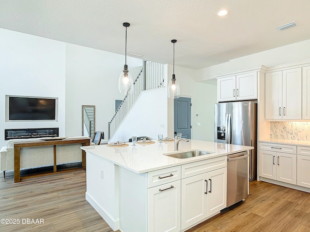 kitchen featuring appliances with stainless steel finishes, sink, an island with sink, and white cabinets