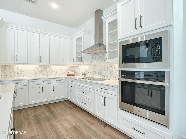 kitchen with white cabinetry, wall chimney range hood, oven, and black electric cooktop