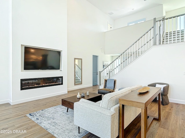 living room featuring a towering ceiling and light hardwood / wood-style flooring