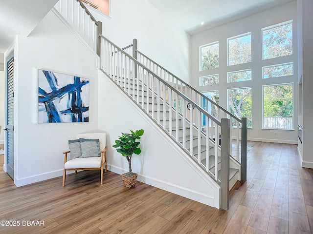 stairway with a towering ceiling and wood-type flooring