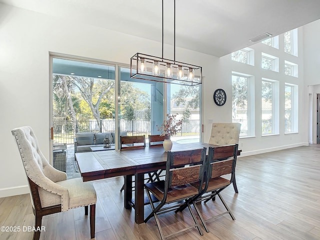 dining area with hardwood / wood-style floors, a towering ceiling, and plenty of natural light