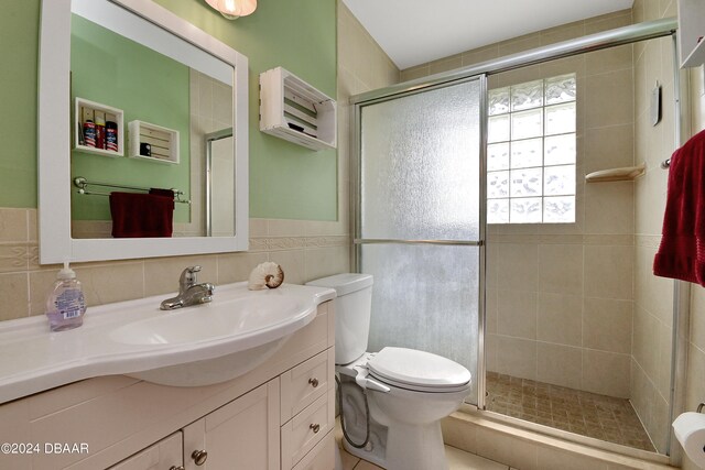 bathroom featuring walk in shower, vanity, tile walls, and toilet