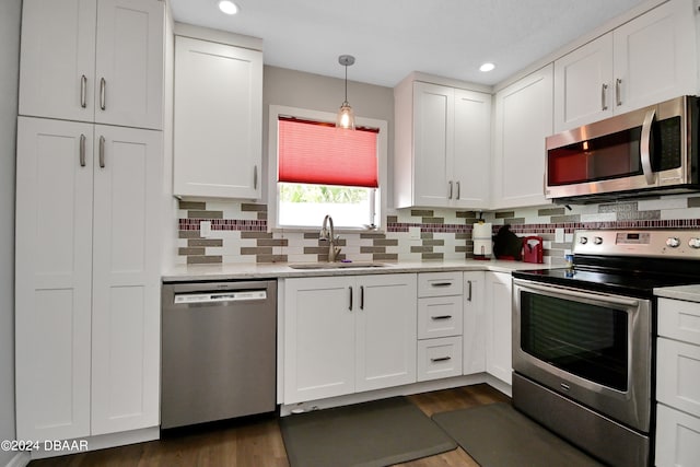 kitchen featuring stainless steel appliances, white cabinets, sink, dark hardwood / wood-style floors, and pendant lighting