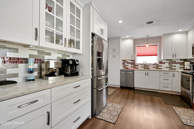 kitchen with white cabinets, appliances with stainless steel finishes, dark hardwood / wood-style floors, and decorative light fixtures