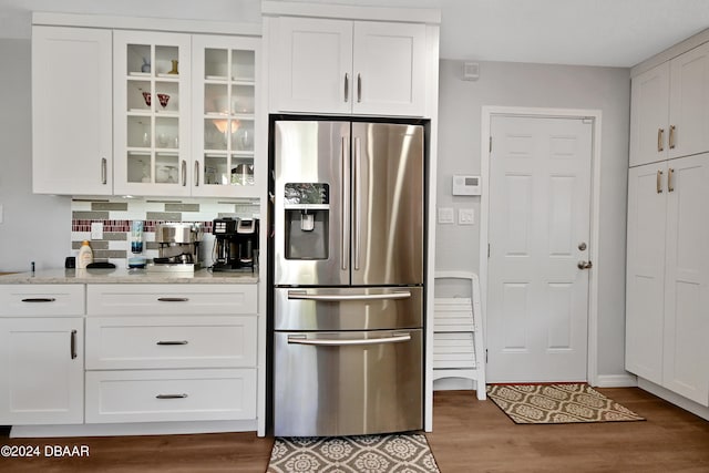 kitchen with light stone countertops, stainless steel fridge, white cabinetry, and wood-type flooring