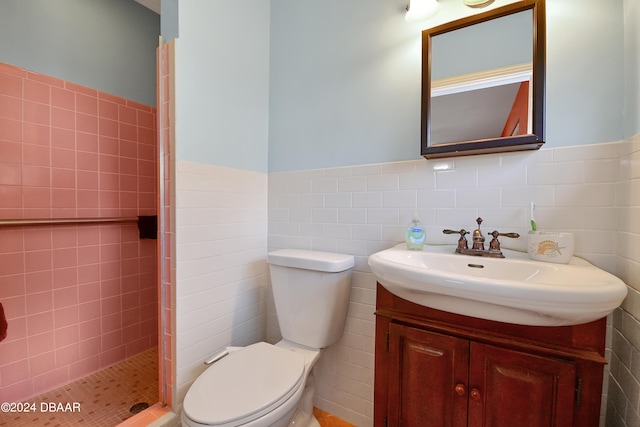 bathroom featuring tile walls, toilet, vanity, and a tile shower