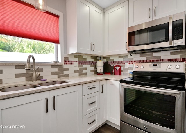 kitchen with white cabinetry, sink, light stone counters, and appliances with stainless steel finishes