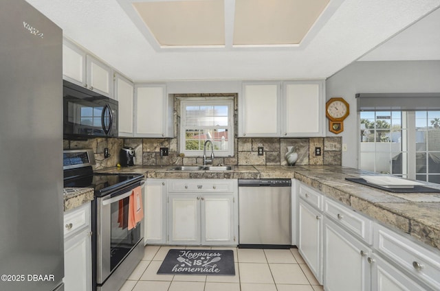 kitchen with stainless steel appliances, a wealth of natural light, a sink, and tile counters