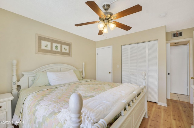 bedroom with light wood finished floors, a closet, visible vents, and a ceiling fan