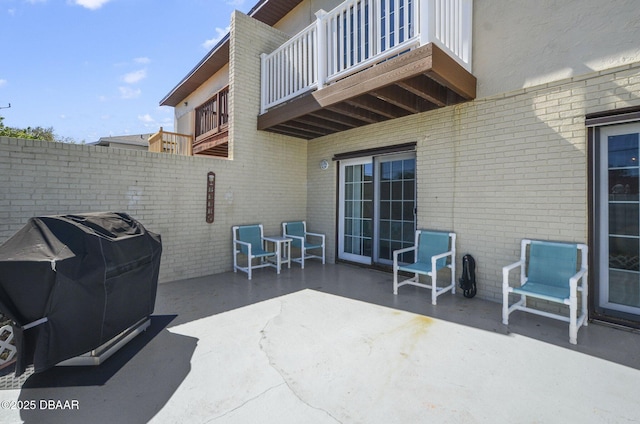 view of patio featuring a grill, a balcony, and fence