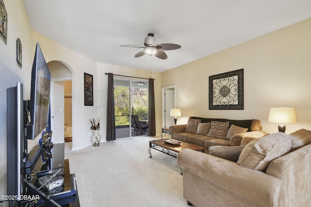 carpeted living room with a textured ceiling and ceiling fan