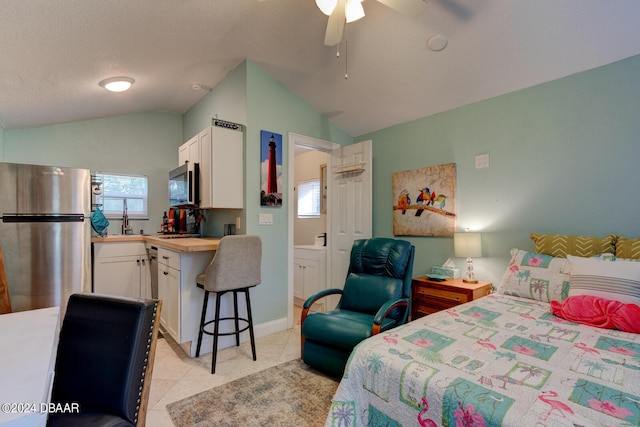 bedroom featuring vaulted ceiling, light tile patterned flooring, stainless steel refrigerator, sink, and ceiling fan