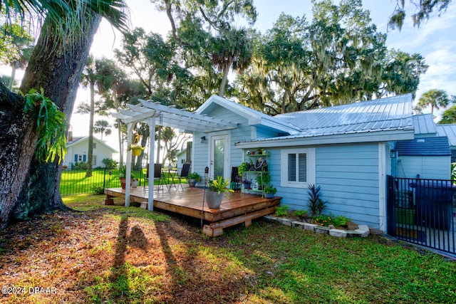 rear view of property with a pergola, a deck, and a lawn