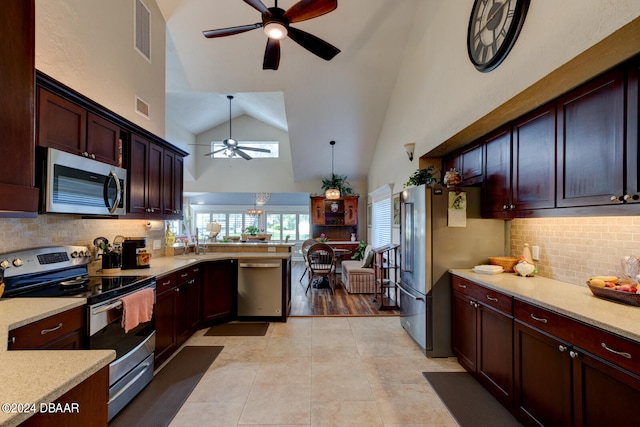 kitchen with appliances with stainless steel finishes, decorative backsplash, hanging light fixtures, ceiling fan, and kitchen peninsula