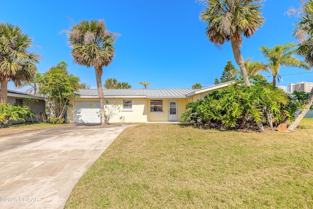 ranch-style home featuring stucco siding, a front yard, metal roof, a garage, and driveway