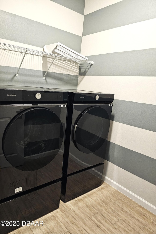 clothes washing area with laundry area, independent washer and dryer, wood finished floors, and baseboards