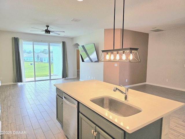 kitchen featuring open floor plan, stainless steel dishwasher, a sink, and gray cabinetry