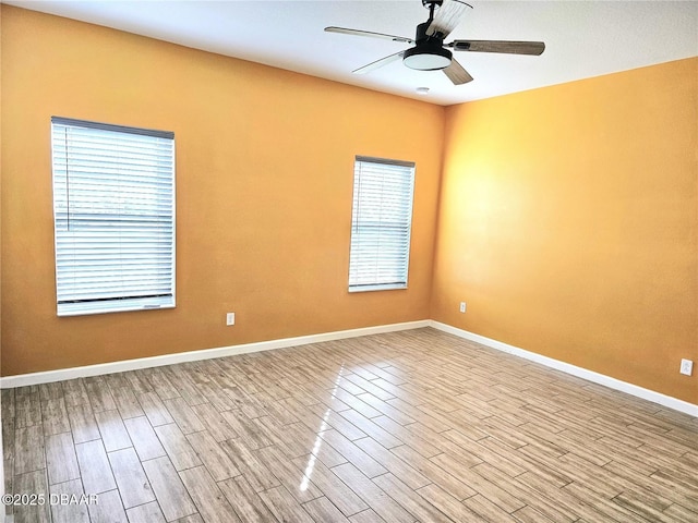 spare room with wood finished floors, a ceiling fan, and baseboards