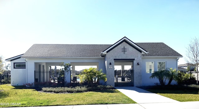 view of front of house featuring a front lawn, a fenced front yard, a shingled roof, and stucco siding