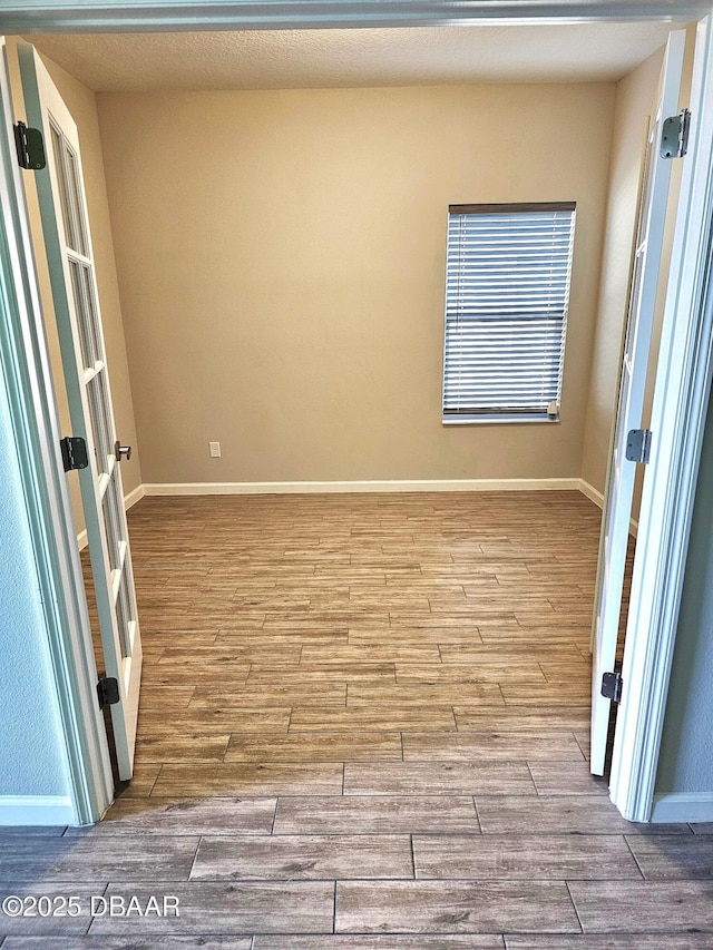 empty room featuring wood finished floors and baseboards