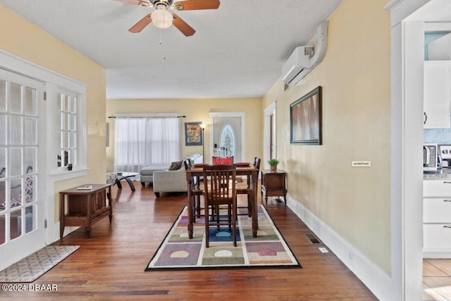 dining space featuring dark wood-type flooring, a wall unit AC, and ceiling fan