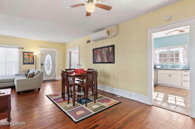 dining room with light wood-type flooring, a wall unit AC, and ceiling fan