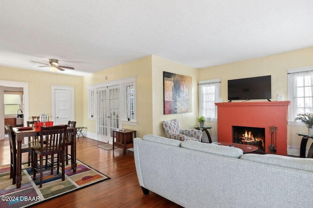 living room featuring dark wood-type flooring, a textured ceiling, and ceiling fan