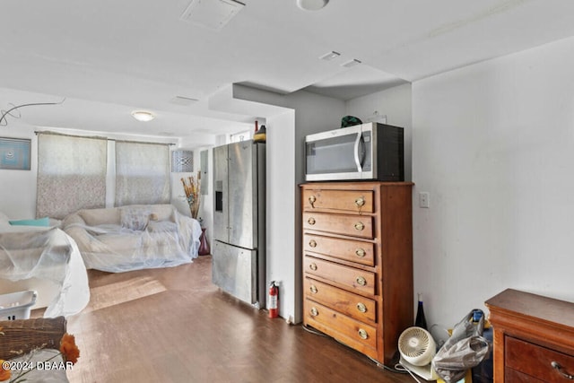 bedroom with dark wood-type flooring and stainless steel fridge with ice dispenser