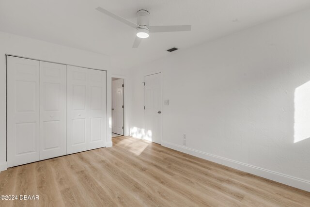 unfurnished bedroom with ceiling fan, a closet, and light wood-type flooring