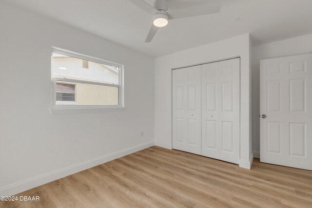 unfurnished bedroom with light hardwood / wood-style flooring, ceiling fan, and a closet