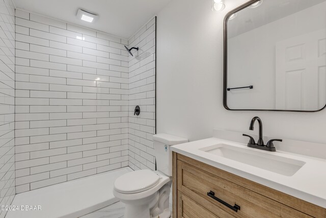 bathroom featuring tiled shower, toilet, and vanity