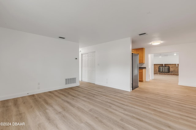 unfurnished room featuring a brick fireplace and light wood-type flooring